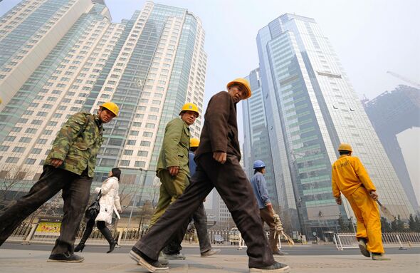 Construction workers walk past high rise