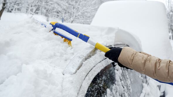 Snow being removed from car using brush